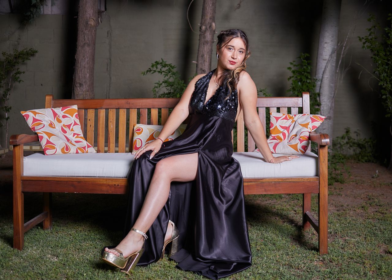 why-choose-us Elegant woman in a black evening dress posing on a bench outdoors, showcasing fashion and style.