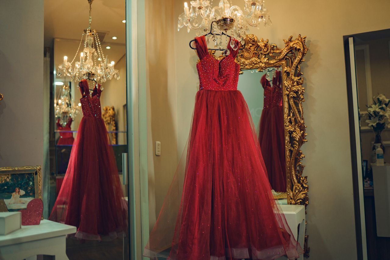 creative A luxurious red evening gown is reflected in a decorative mirror under a chandelier.