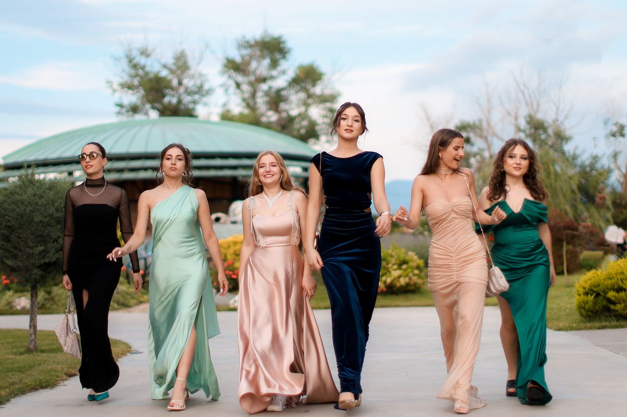 digital A group of six women in elegant evening dresses walking confidently outdoors, showcasing fashion and style.